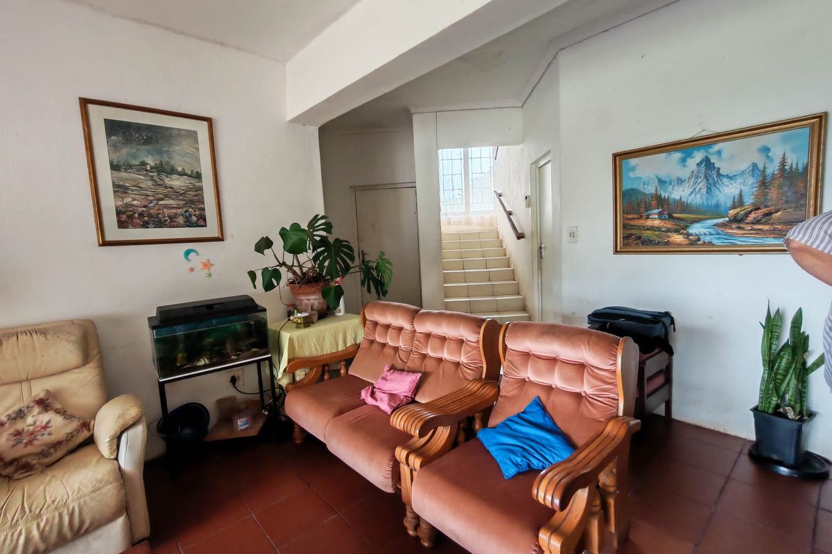 A living area featuring terracotta-style floor tiles and a staircase with a wooden handrail leading to the upper level.