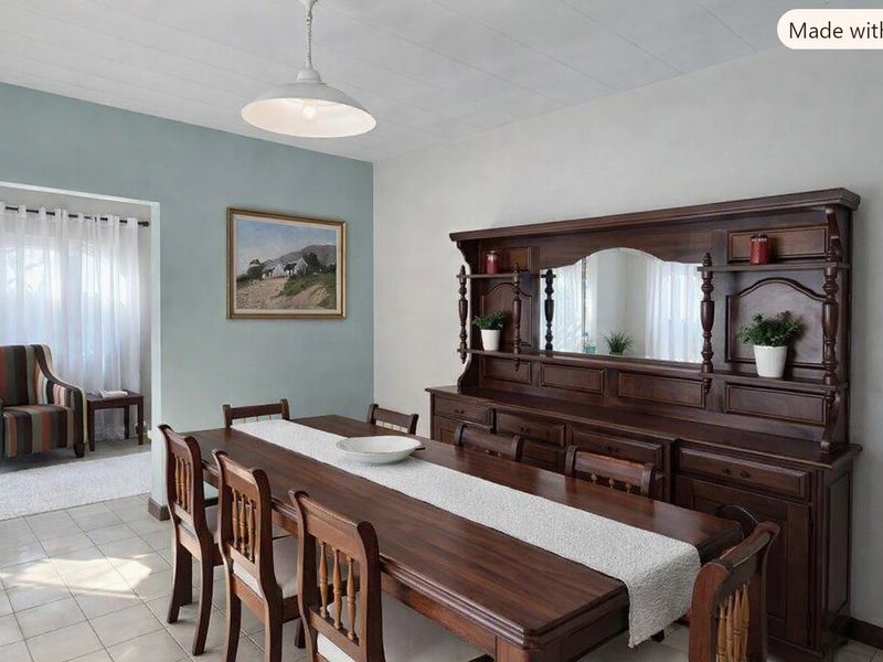 A dining room featuring tiled flooring and a central pendant light fixture, with an adjacent transition area visible through the doorway.