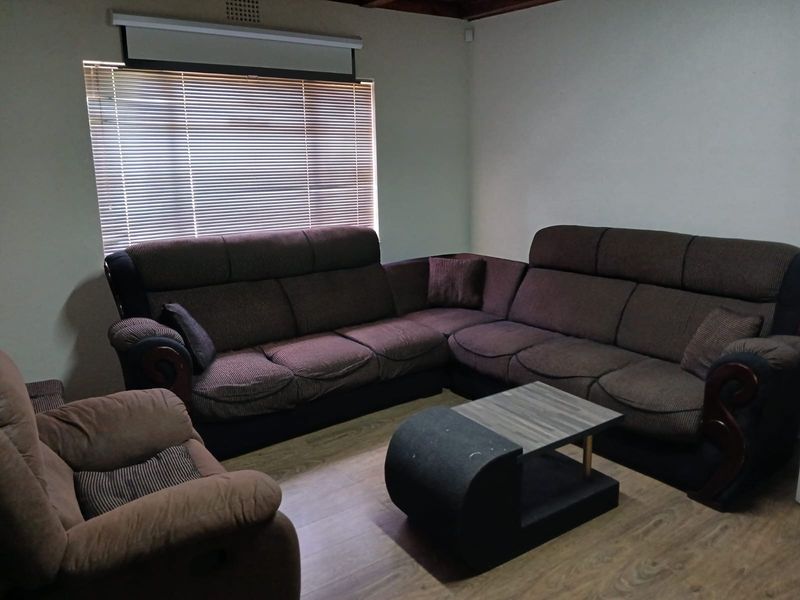 A living room featuring laminate flooring, venetian blinds, and a mounted projector screen, providing a functional space for entertainment.
