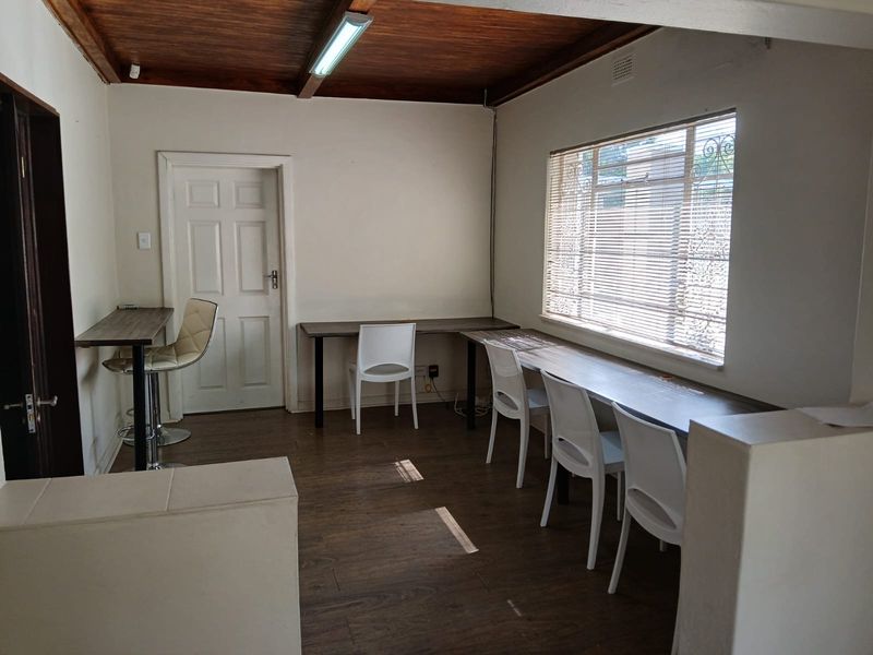 A functional office space featuring laminate flooring, a timber ceiling, and a window with security bars, providing a practical work environment.