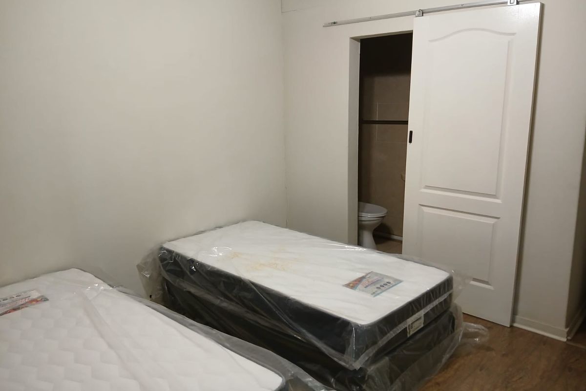A bedroom featuring laminate flooring and a sliding barn door leading to an en-suite bathroom.