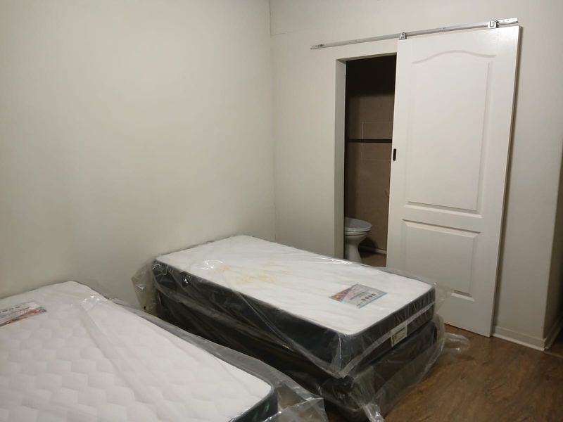 A bedroom featuring laminate flooring and a sliding barn door leading to an en-suite bathroom.