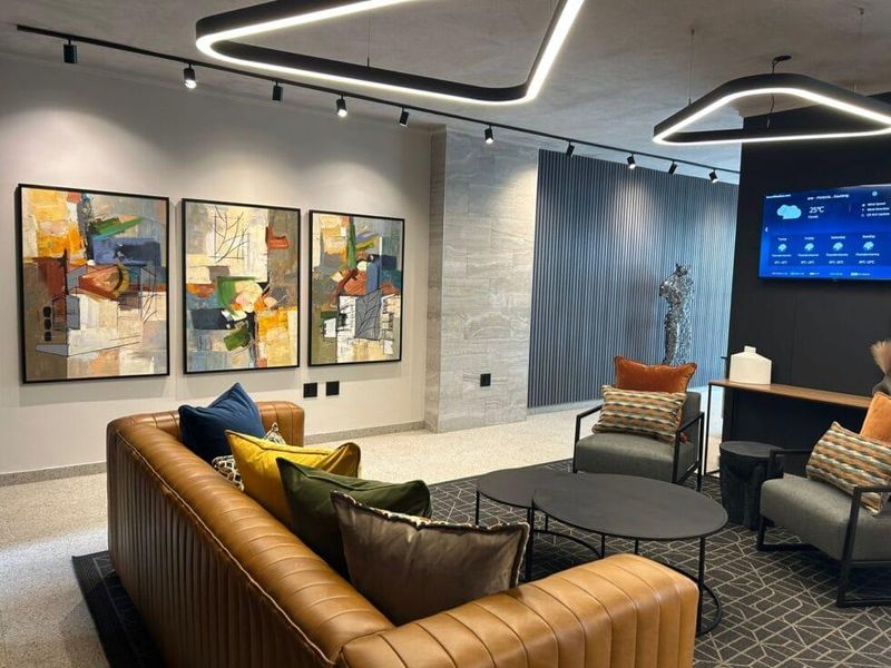 Modern living area featuring stylish track lighting, a textured stone feature wall, contemporary slatted paneling, and polished terrazzo flooring.