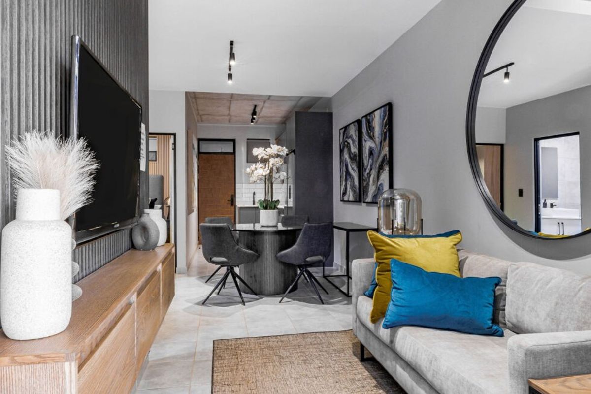 Modern open-plan living and dining area featuring contemporary track lighting, tiled floors, and a stylish textured feature wall.