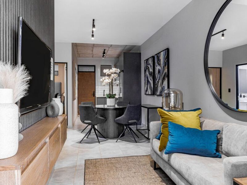 Modern open-plan living and dining area featuring contemporary track lighting, tiled floors, and a stylish textured feature wall.