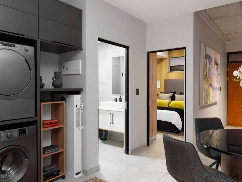 A functional laundry area featuring built-in cabinetry and stacked laundry appliances, providing convenient access to the adjacent bathroom and bedroom.