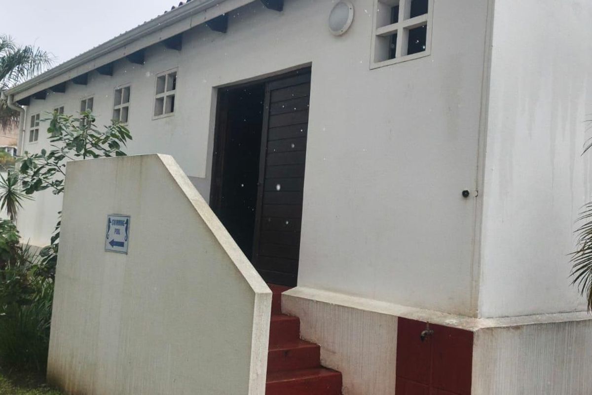 Exterior view of the building rear featuring concrete steps, a timber door, and perimeter electric fencing.