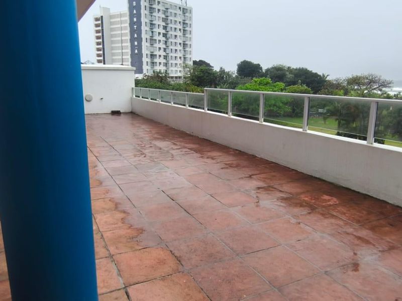 Spacious balcony featuring tiled flooring and a glass balustrade, offering an open outdoor area with views of the surrounding landscape.