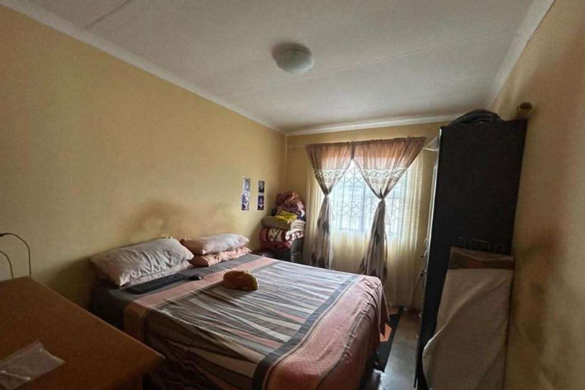 A standard bedroom featuring security bars on the window and painted walls, requiring cosmetic updates to improve the overall aesthetic.