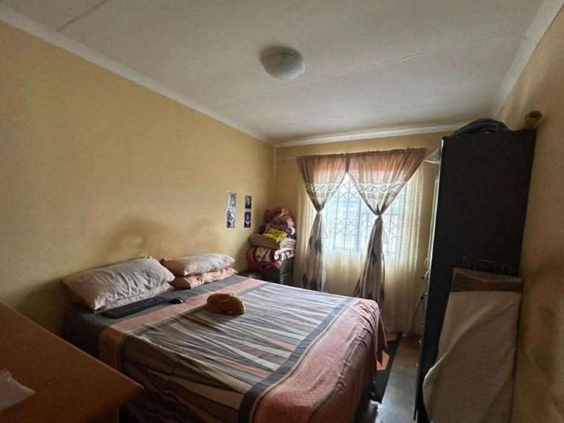 A standard bedroom featuring security bars on the window and painted walls, requiring cosmetic updates to improve the overall aesthetic.