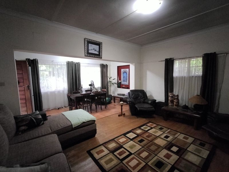 Open plan living and dining area featuring laminate flooring, cove cornicing, and a decorative recessed wall niche.