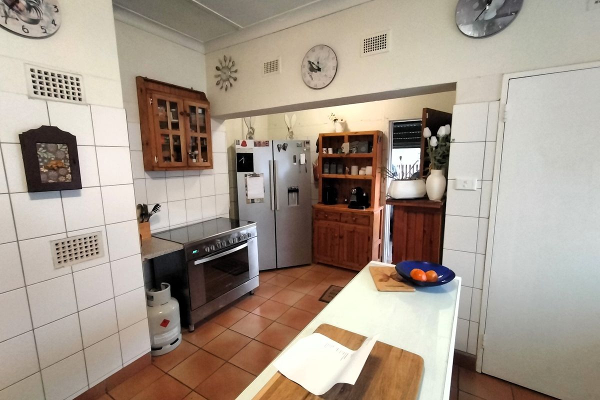 A functional kitchen featuring tiled flooring, a tiled splashback, and a freestanding oven, offering a practical layout with potential for modern updates.