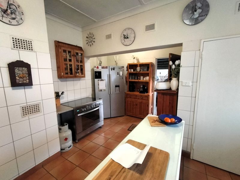 A functional kitchen featuring tiled flooring, a tiled splashback, and a freestanding oven, offering a practical layout with potential for modern updates.