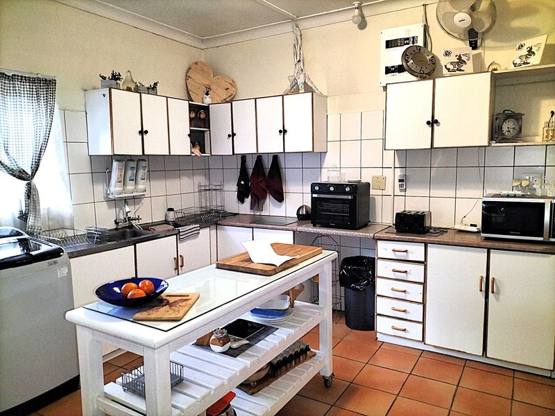 A functional kitchen featuring white cabinetry, tiled backsplash, and tiled flooring. The space offers ample storage and a central prep area.