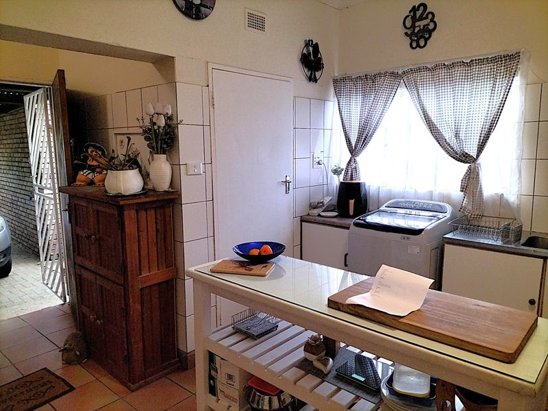 A functional laundry area featuring tiled walls, built-in cabinetry, and a sink, with direct access to the exterior.