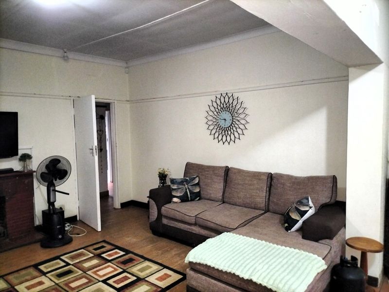A living room featuring laminate flooring and coved ceilings, requiring cosmetic updates to improve the overall finish and aesthetic appeal.