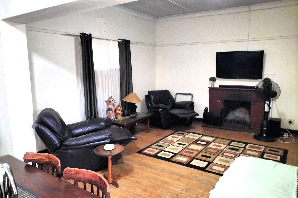 A living room featuring a brick fireplace and hardwood flooring, requiring cosmetic updates to improve the overall aesthetic and condition of the space.