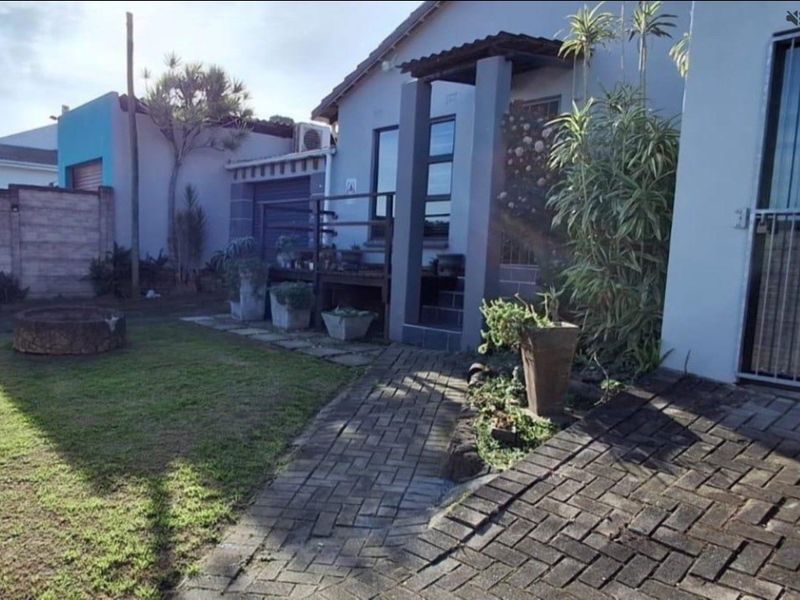 Front exterior view of the house featuring a paved driveway, walkway, and a covered entrance porch with a small garden area.