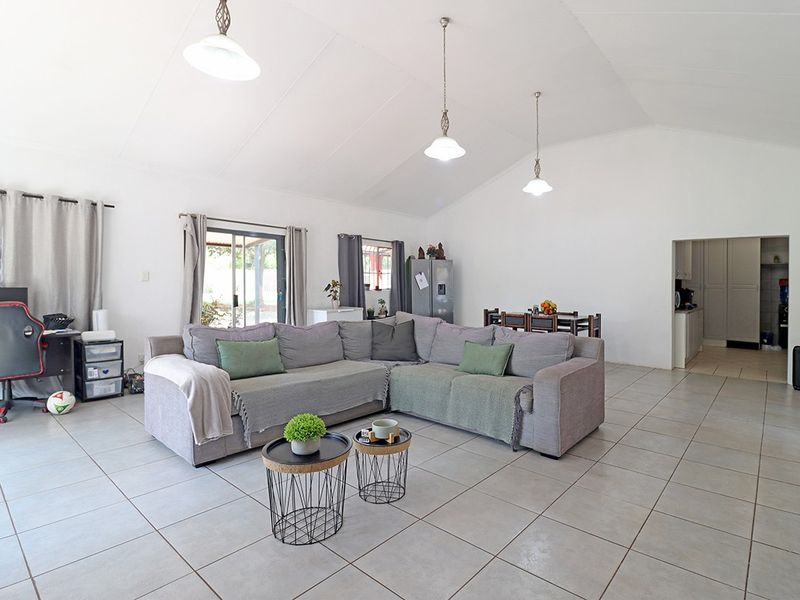 Spacious open-plan living area featuring vaulted ceilings, neutral ceramic floor tiles, and sliding glass doors providing access to the exterior.