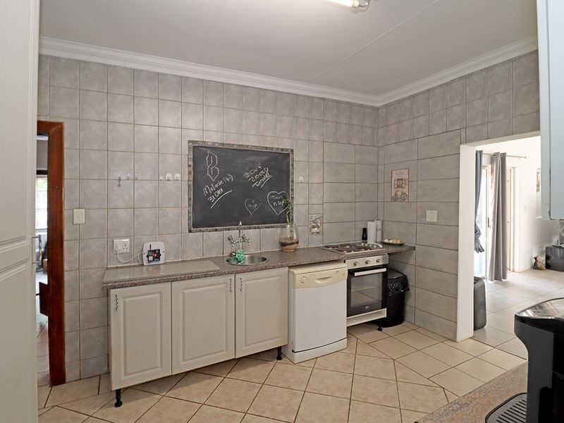A functional kitchen featuring tiled walls and flooring, granite countertops, built-in cabinetry, and integrated oven and hob.