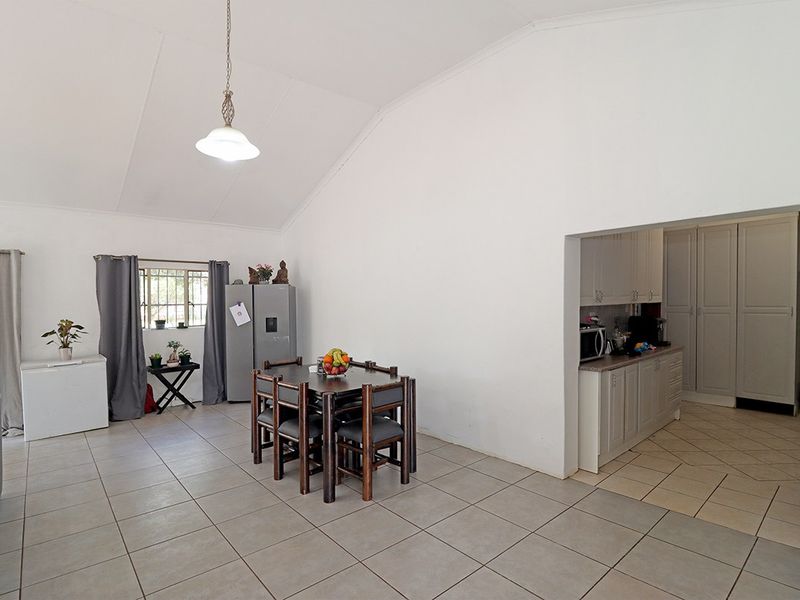 Open plan living and dining area featuring vaulted ceilings, tiled floors, and an adjacent kitchen with built-in cabinetry and laminate countertops.