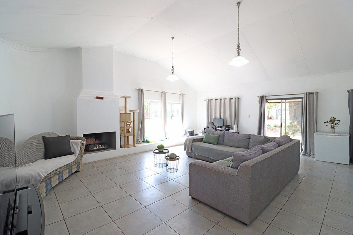 Spacious living room featuring a built-in fireplace, vaulted ceilings, tiled flooring, and multiple sliding glass doors providing natural light and garden access.