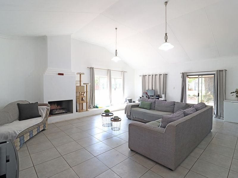 Spacious living room featuring a built-in fireplace, vaulted ceilings, tiled flooring, and multiple sliding glass doors providing natural light and garden access.