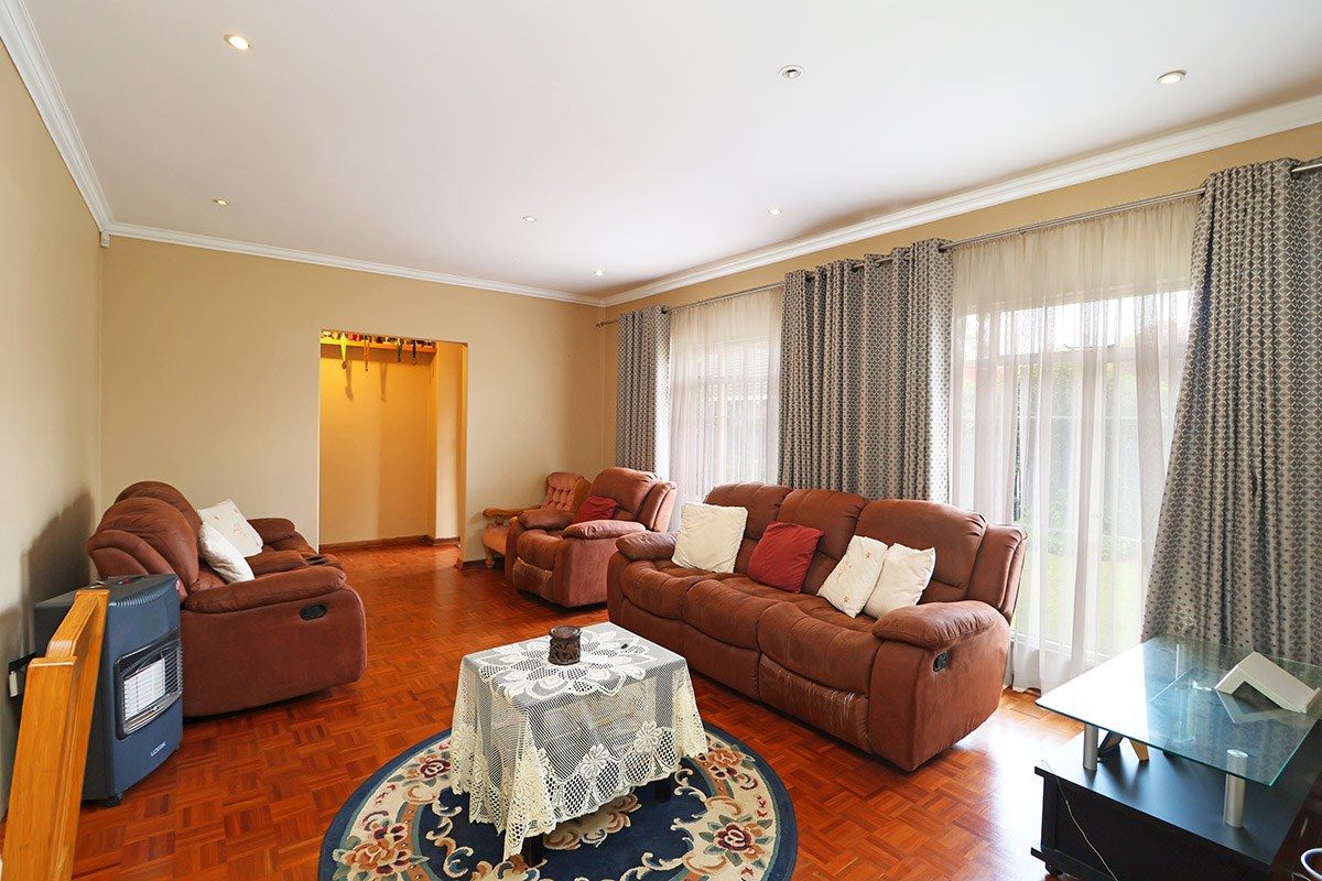 Spacious living room featuring warm parquet flooring, recessed downlighting, and large sliding glass doors that provide access to the garden area.