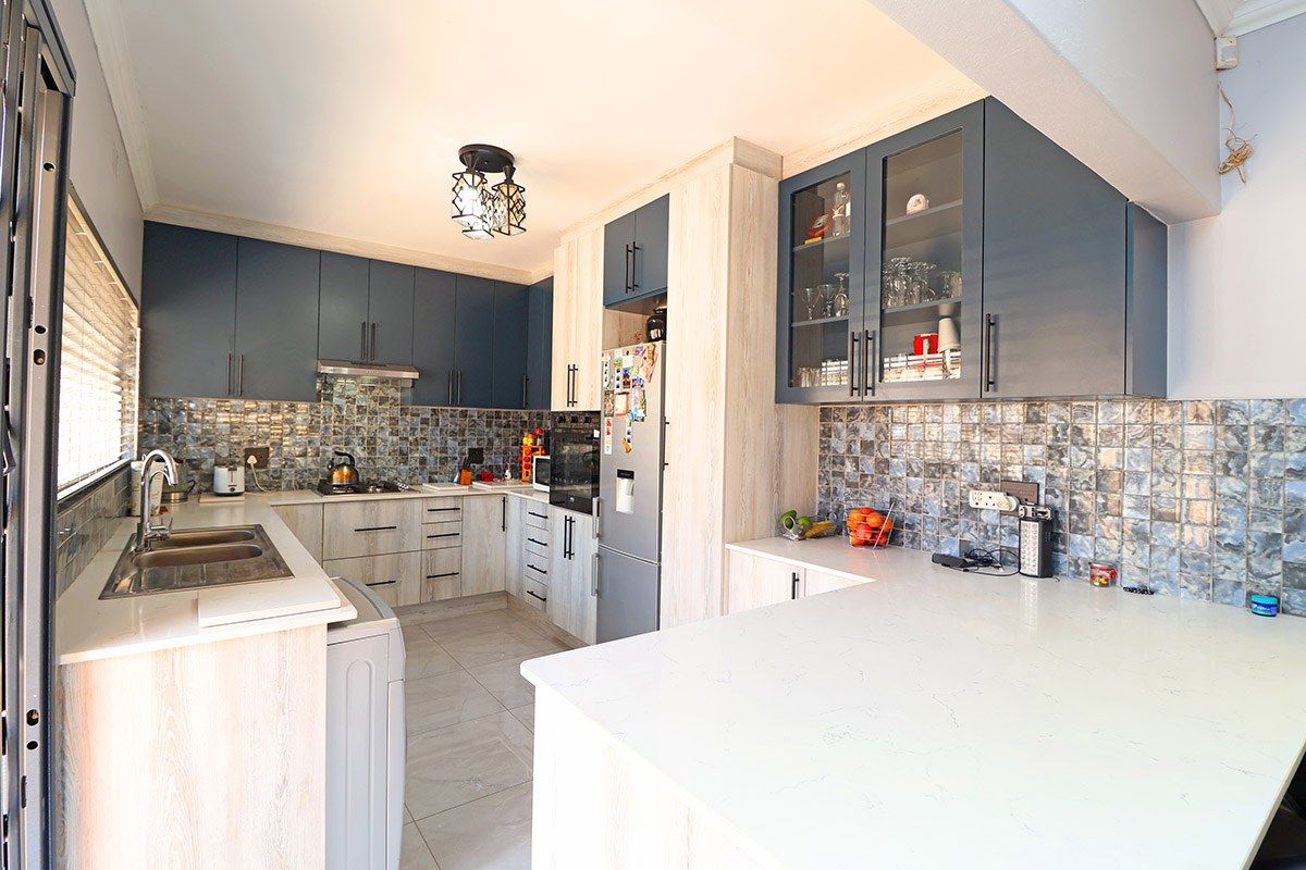 Modern kitchen featuring two-tone cabinetry, quartz countertops, mosaic tile backsplash, and integrated appliances, offering a functional and stylish cooking space.