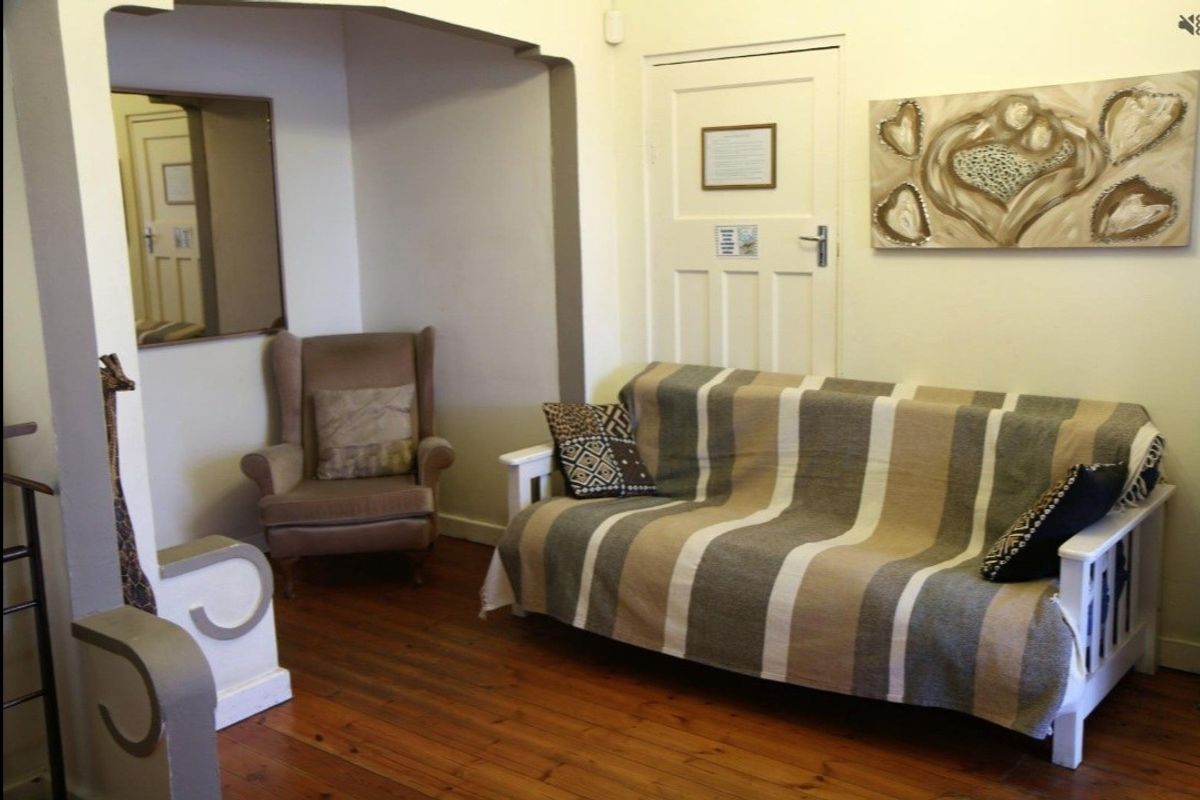 A cozy living area featuring warm hardwood flooring, a distinctive architectural archway, and a classic panelled door.