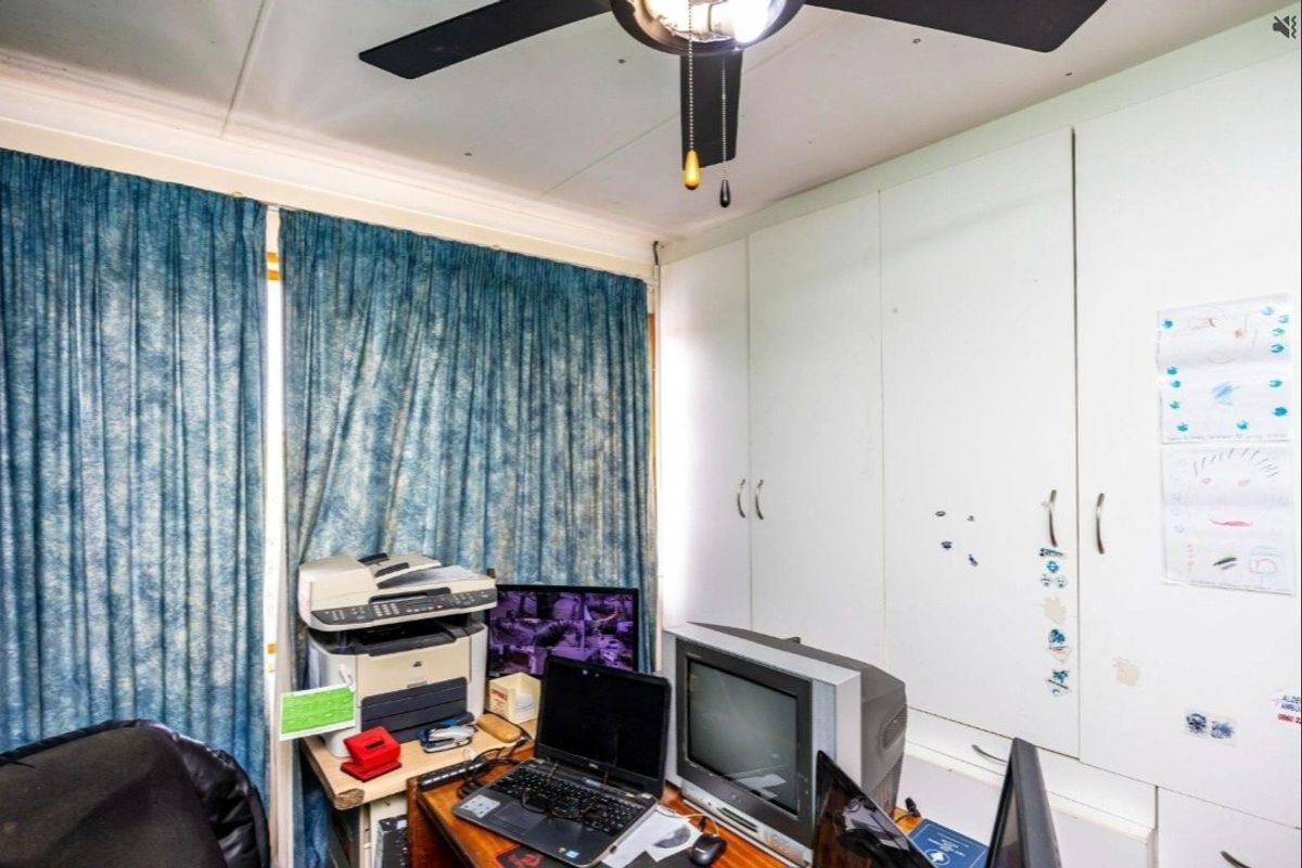 A bedroom featuring built-in cupboards and a ceiling fan, currently utilized as a home office space.