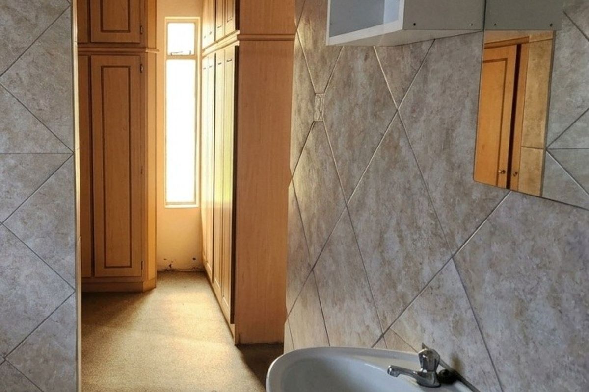 A functional bathroom featuring a pedestal basin, tiled surfaces, and extensive built-in cabinetry, offering ample storage space.