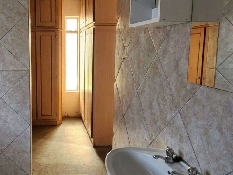 A functional bathroom featuring a pedestal basin, tiled surfaces, and extensive built-in cabinetry, offering ample storage space.