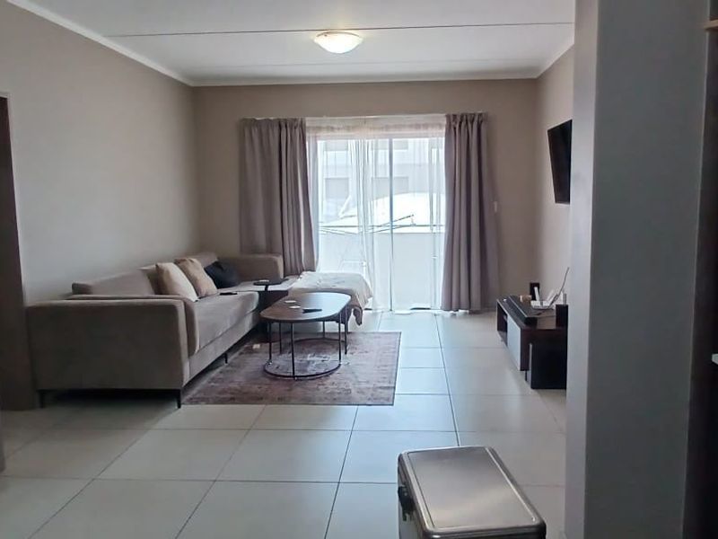 Open-plan living area featuring tiled flooring, neutral wall tones, and a sliding glass door providing access to the balcony.