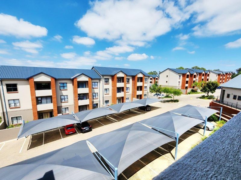 Elevated view of an apartment complex featuring multiple multi-story buildings, paved parking areas, and installed shade cloth carports.