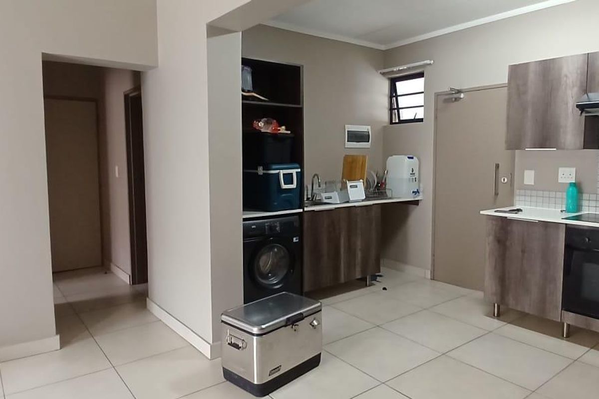 A functional kitchen featuring built-in cabinetry, an integrated oven and hob, extractor fan, and tiled flooring with a neutral color palette.