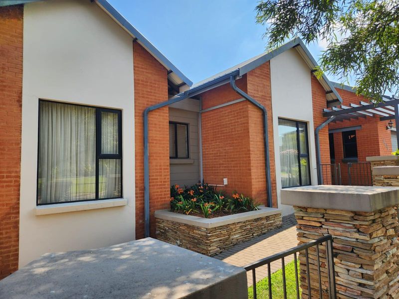 Front elevation of a modern house featuring a combination of brick and rendered walls, stone-clad planter box, and aluminium window frames.
