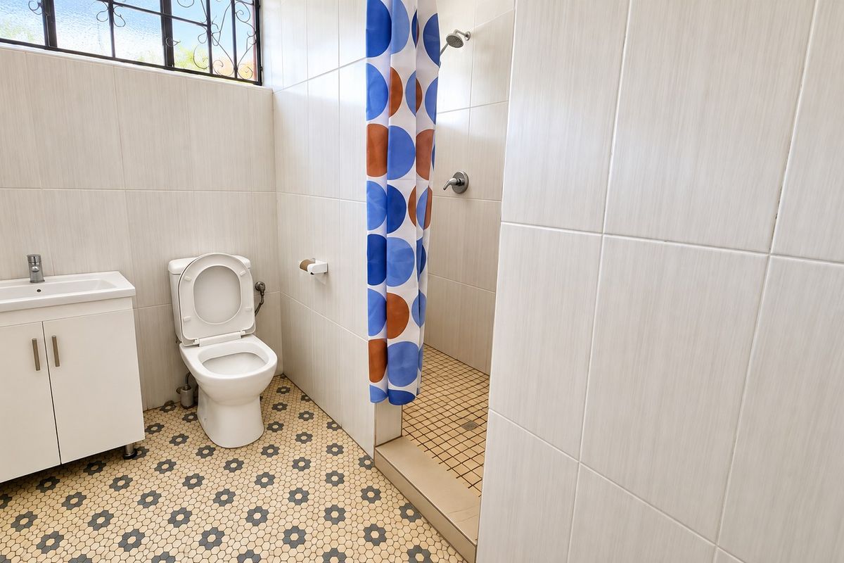 A functional bathroom featuring a vanity cabinet, toilet, and a walk-in shower with tiled finishes throughout.