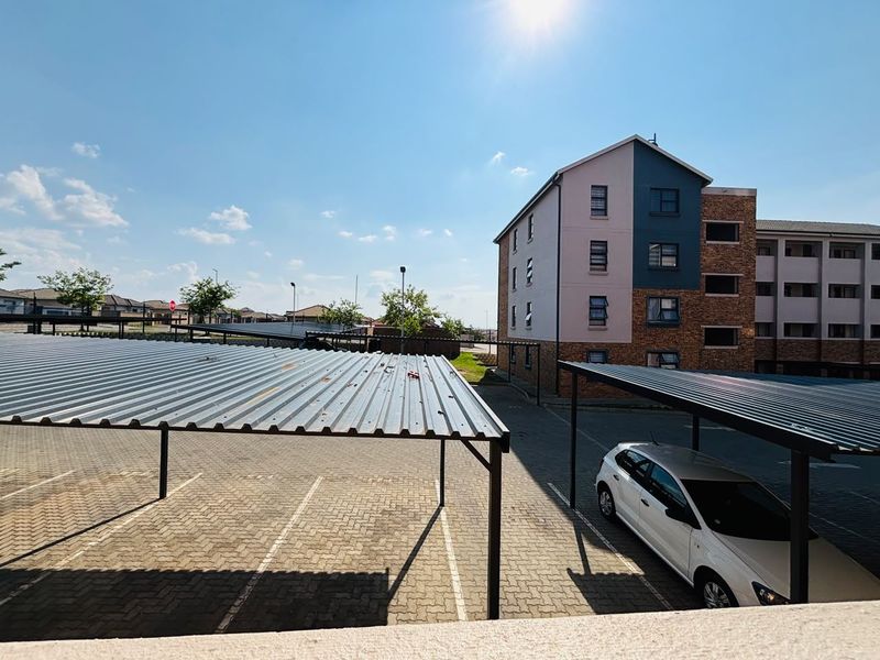 Exterior view of the apartment complex featuring covered parking bays and paved driveway areas.