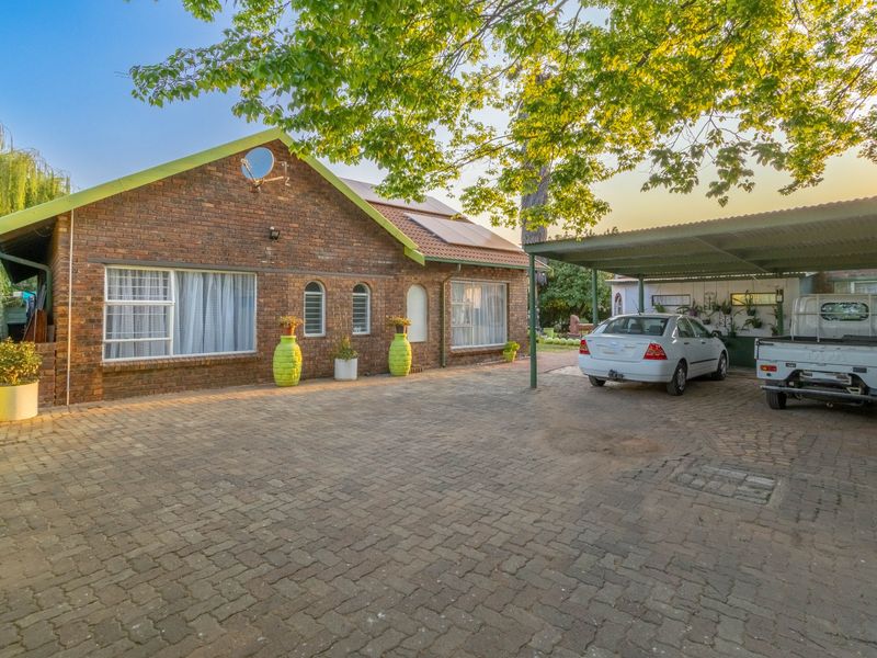 Front view of a face brick house featuring a paved driveway, carport, and solar panels installed on the roof.