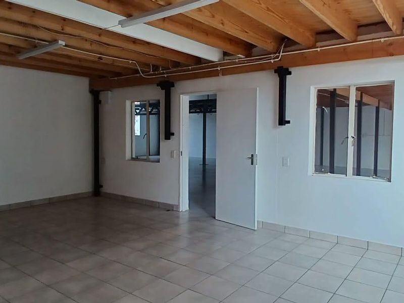 An open-plan industrial utility space featuring exposed timber ceiling beams, tiled flooring, and steel structural columns, offering a versatile blank canvas.