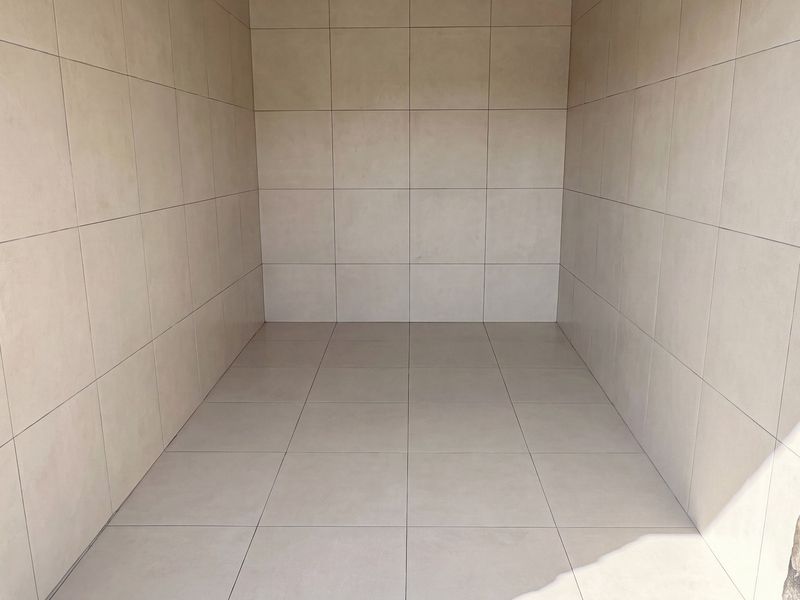 A clean, empty utility space featuring neutral floor-to-ceiling tiling and decorative stone-clad pillars at the entrance.