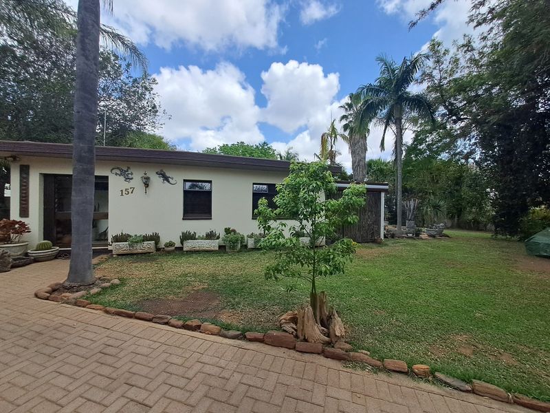 Front view of a residential property featuring a paved driveway, well-maintained lawn, and established garden landscaping.