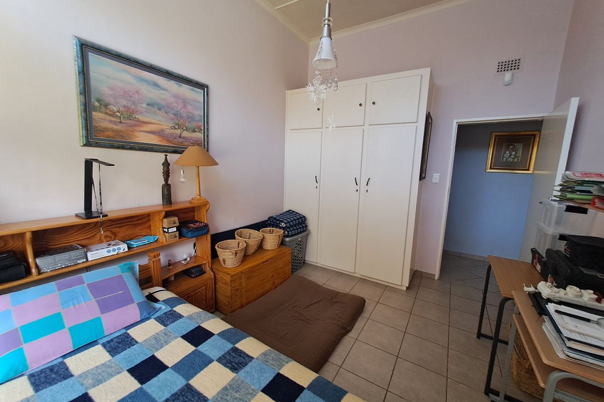 A bedroom featuring built-in cupboards, tiled flooring, and a central light fixture, offering a functional space with potential for modernization.
