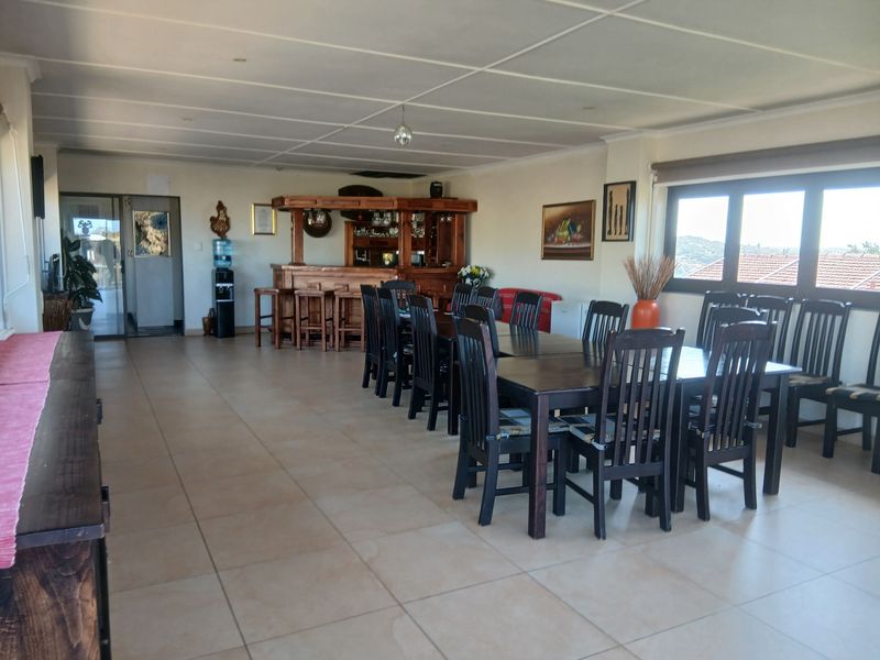 Spacious entertainment area featuring a built-in wooden bar, tiled flooring, and large windows providing natural light.