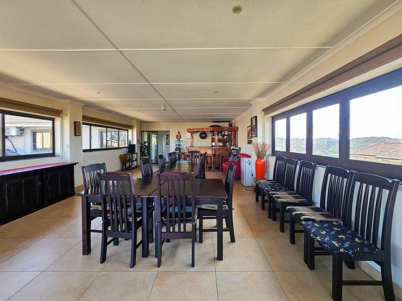 Spacious open-plan living and dining area featuring large windows, tiled flooring, and a built-in bar, offering a versatile layout for entertaining.