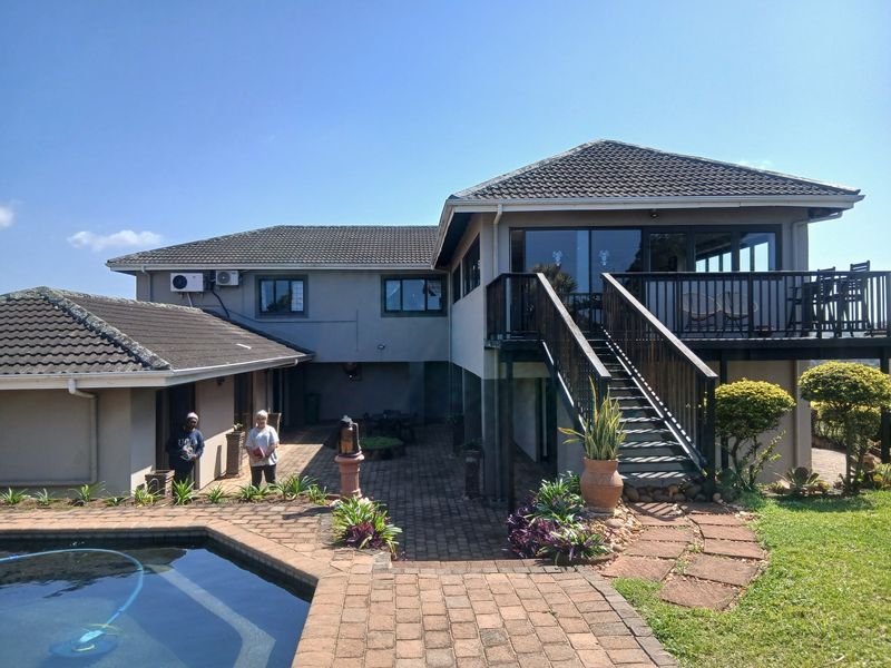 Rear view of the property featuring a swimming pool, paved patio area, and an elevated wooden deck with an external staircase.