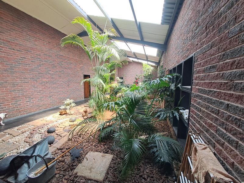 An enclosed courtyard or atrium featuring exposed brick walls, a translucent roof structure, and integrated shelving, providing a unique semi-outdoor living space.