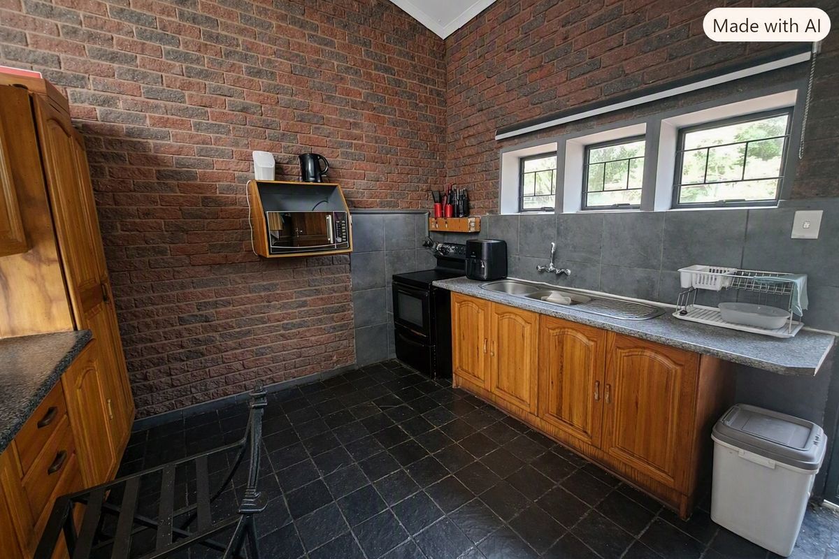A kitchen featuring exposed brick walls, wooden cabinetry, a stainless steel sink, and a freestanding stove with tiled flooring.