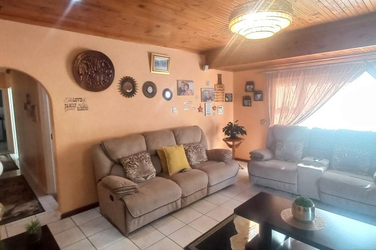 A living room featuring a timber-clad ceiling, ceramic floor tiles, and a central flush mount light fixture.